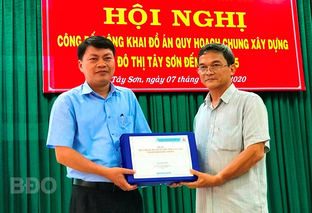 Ông Trần Viết Bảo (bên phải) trao đồ án Quy hoạch chung xây dựng đô thị Tây Sơn đến năm 2035 cho Chủ tịch UBND huyện Tây Sơn Phan Chí Hùng